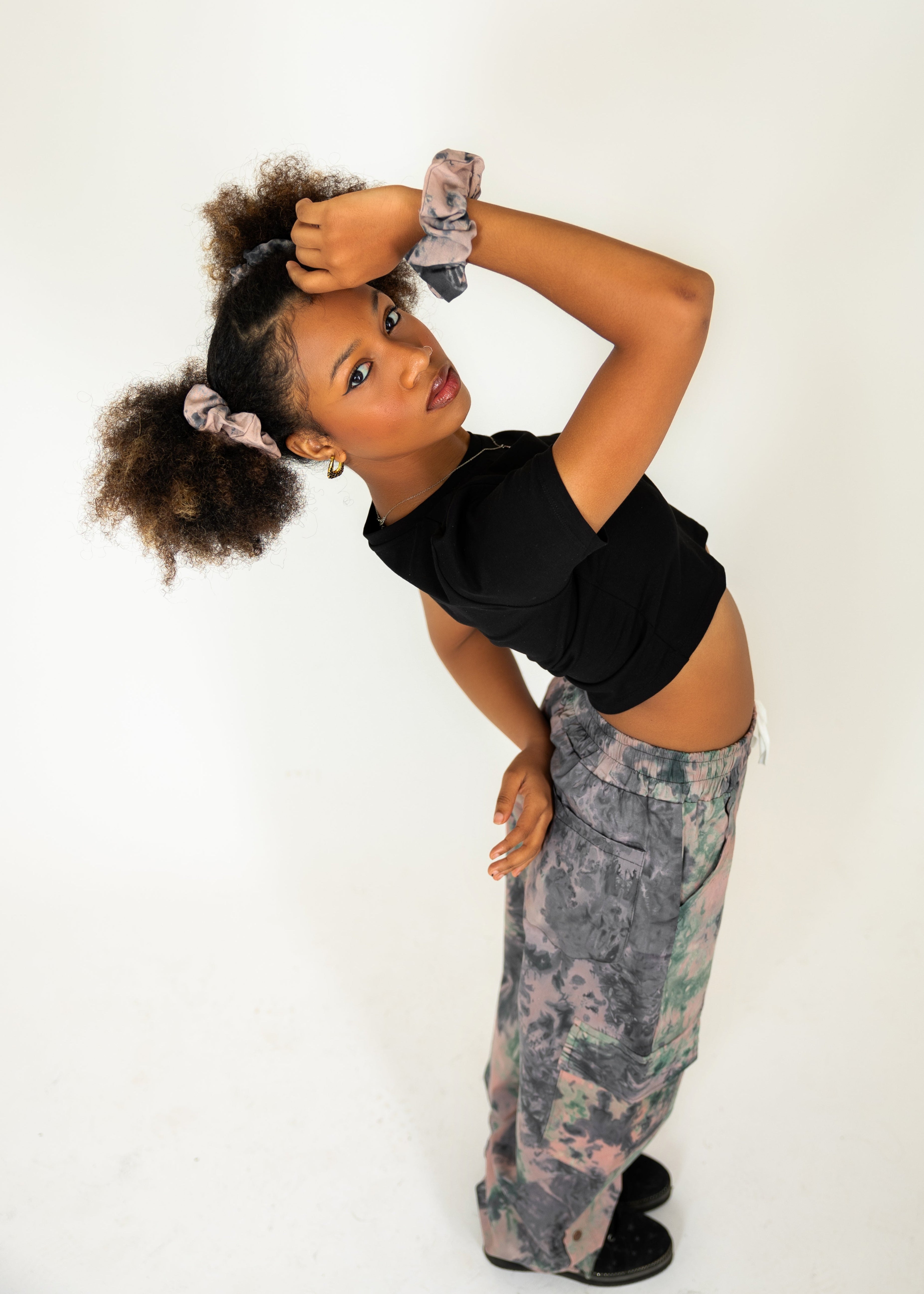Person wearing a black top with Earthy scrunchie and Earthy pants against a white background